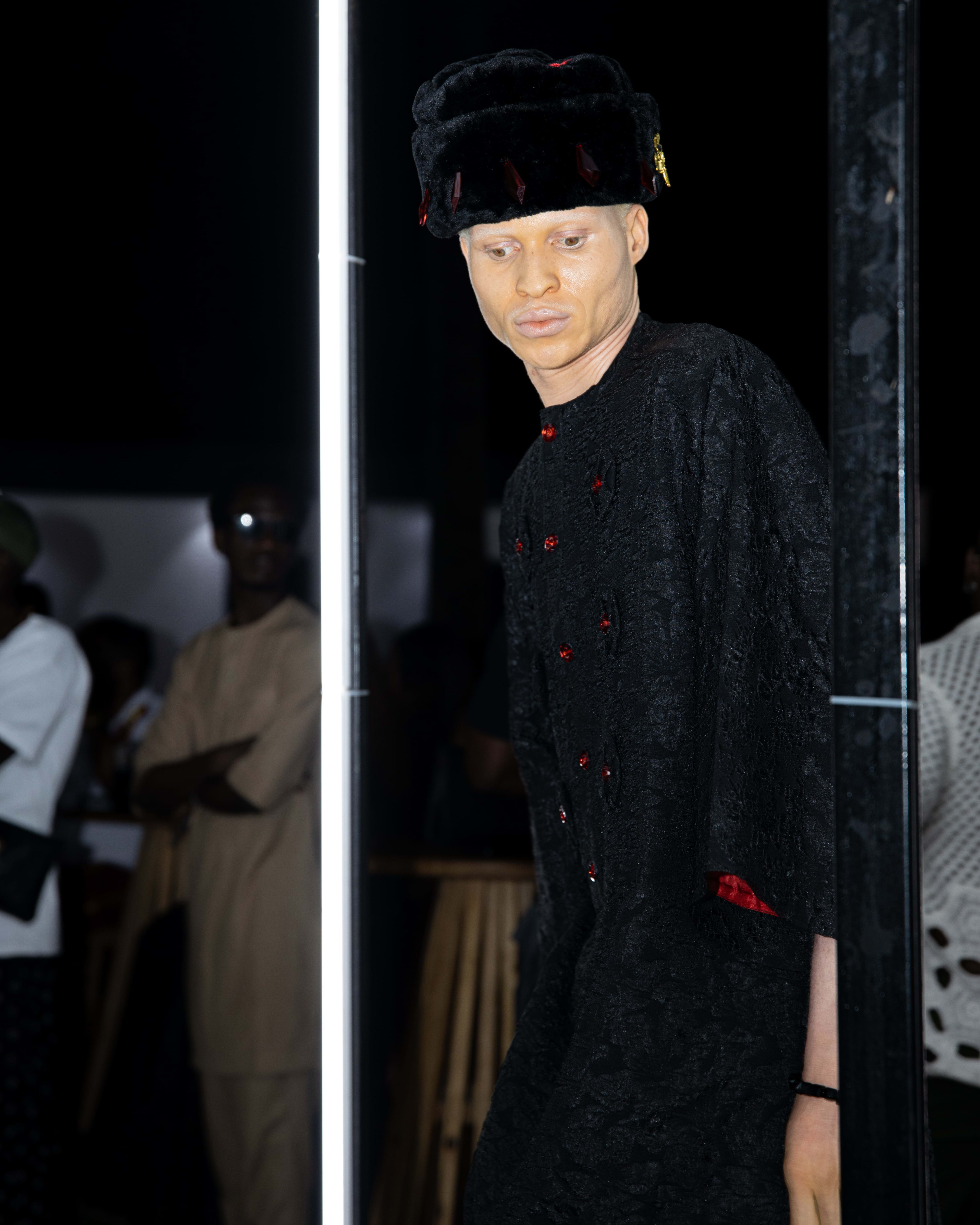 A model in a dark beaded caftan and velvet hat on the runway