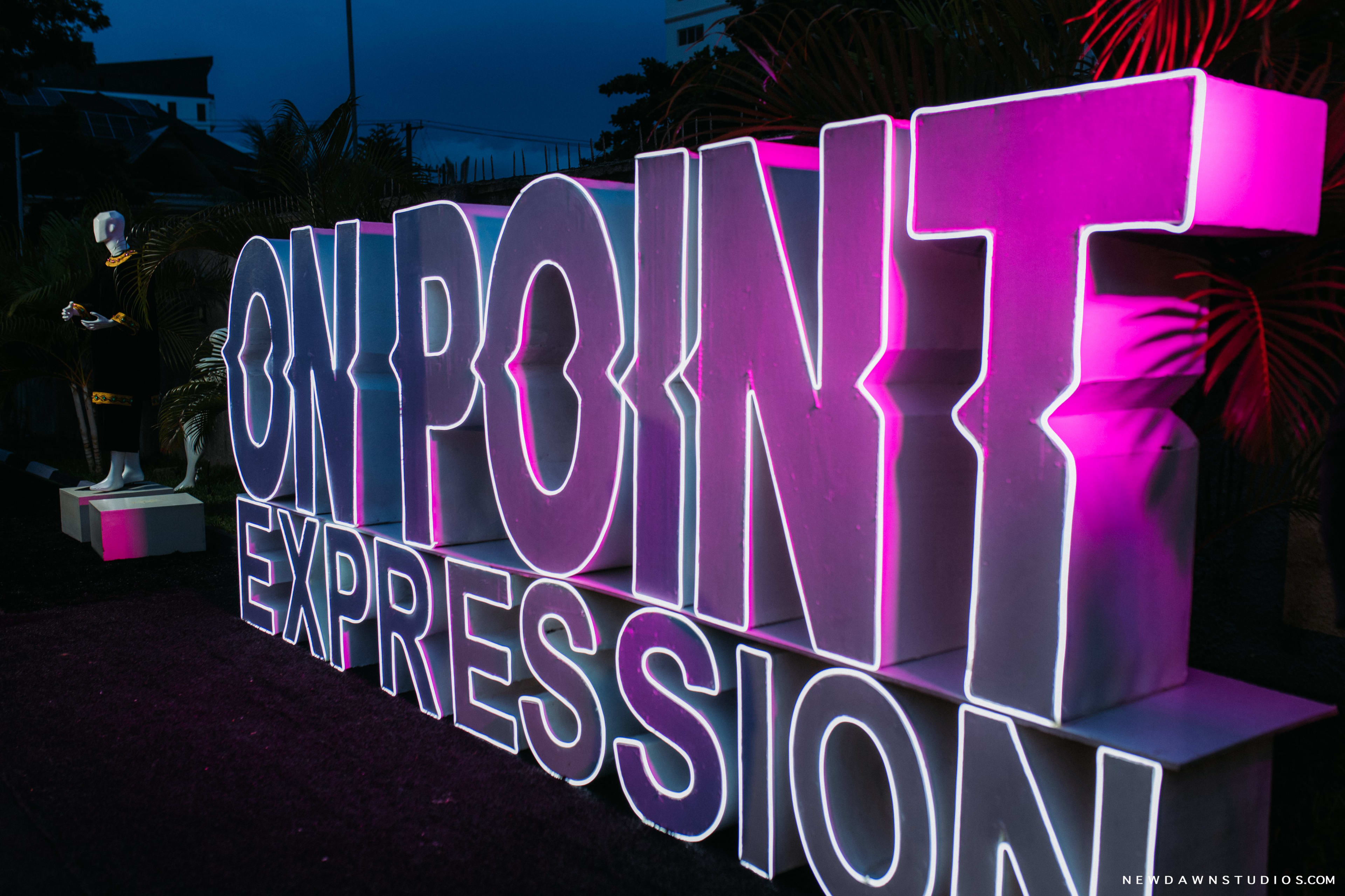 The illuminated OnPoint Expression marquee sign glowing magenta against the night sky
