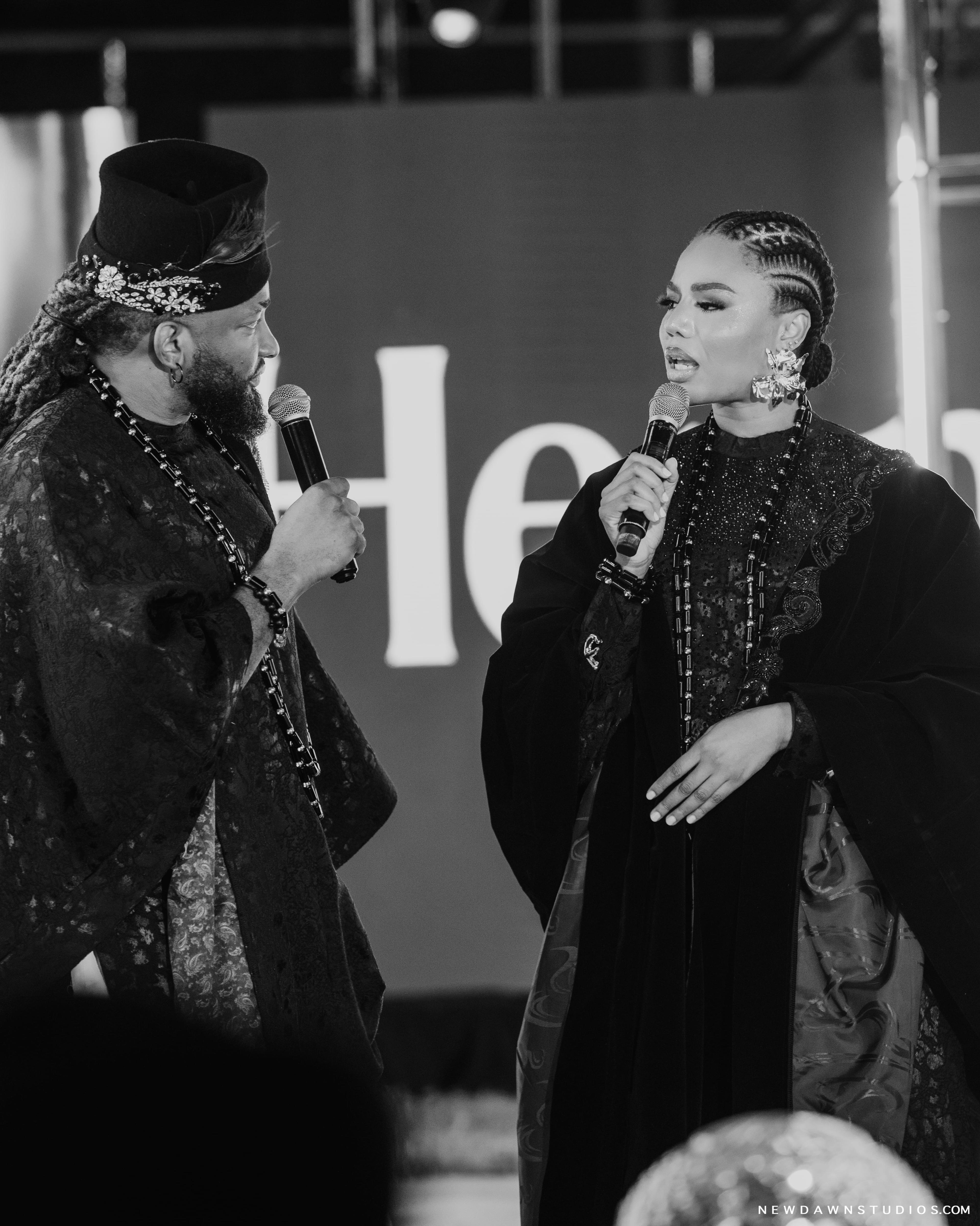 A black-and-white shot of the hosts both addressing the crowd side by side