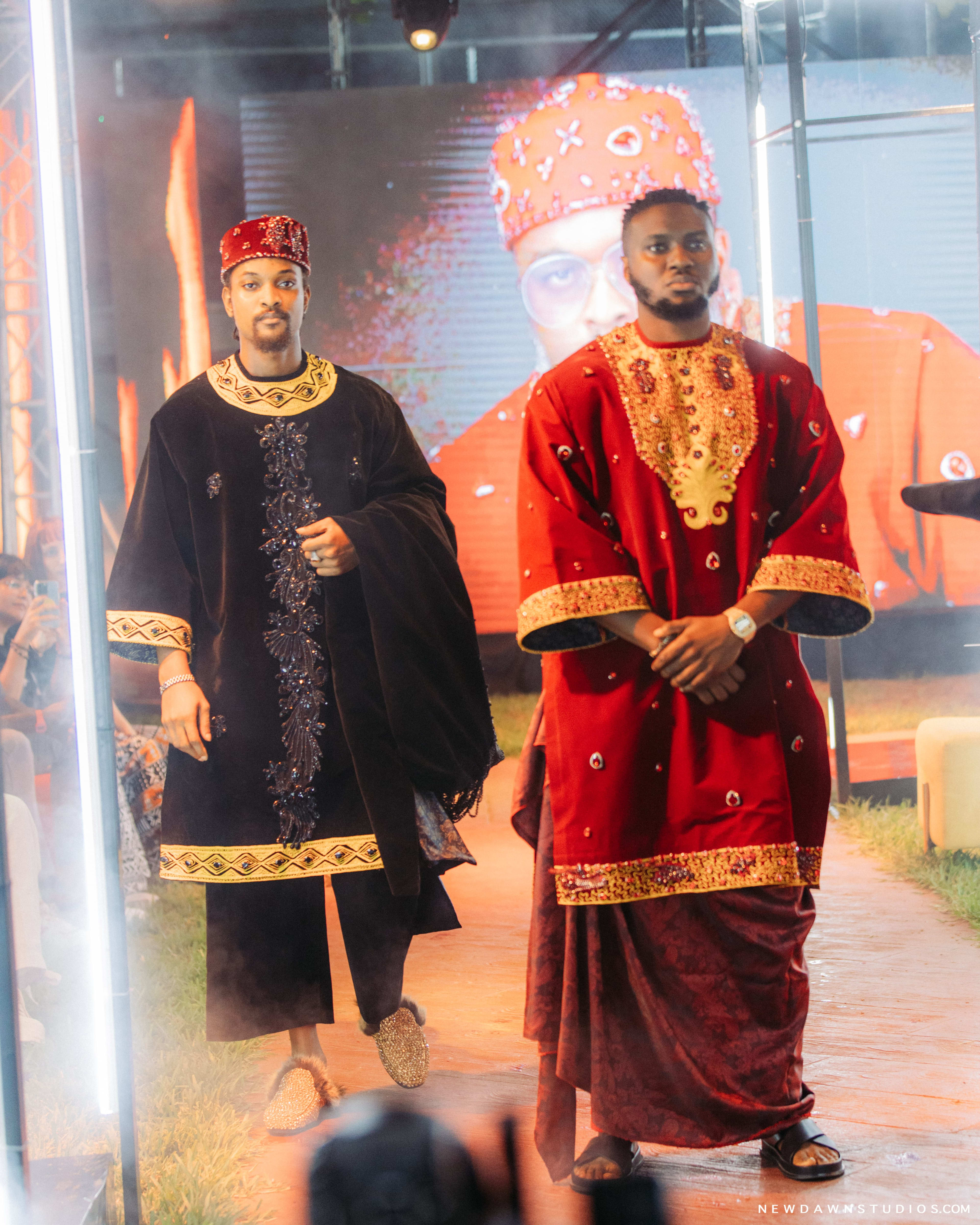 Two men in ceremonial red and black velvet robes walking the runway together