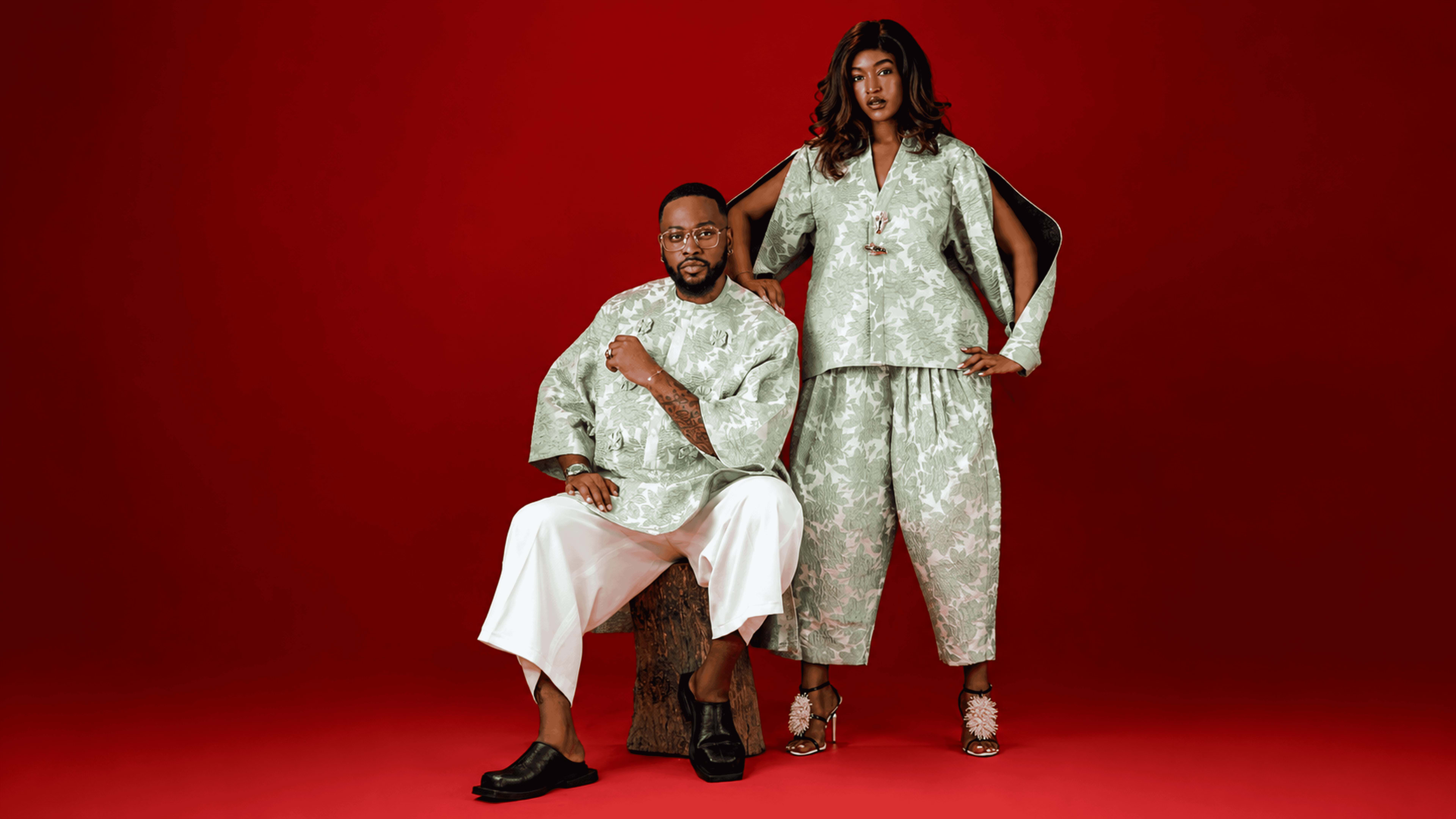 Two OnPoint models in matching sage-green printed co-ord sets, studio portrait on a red backdrop