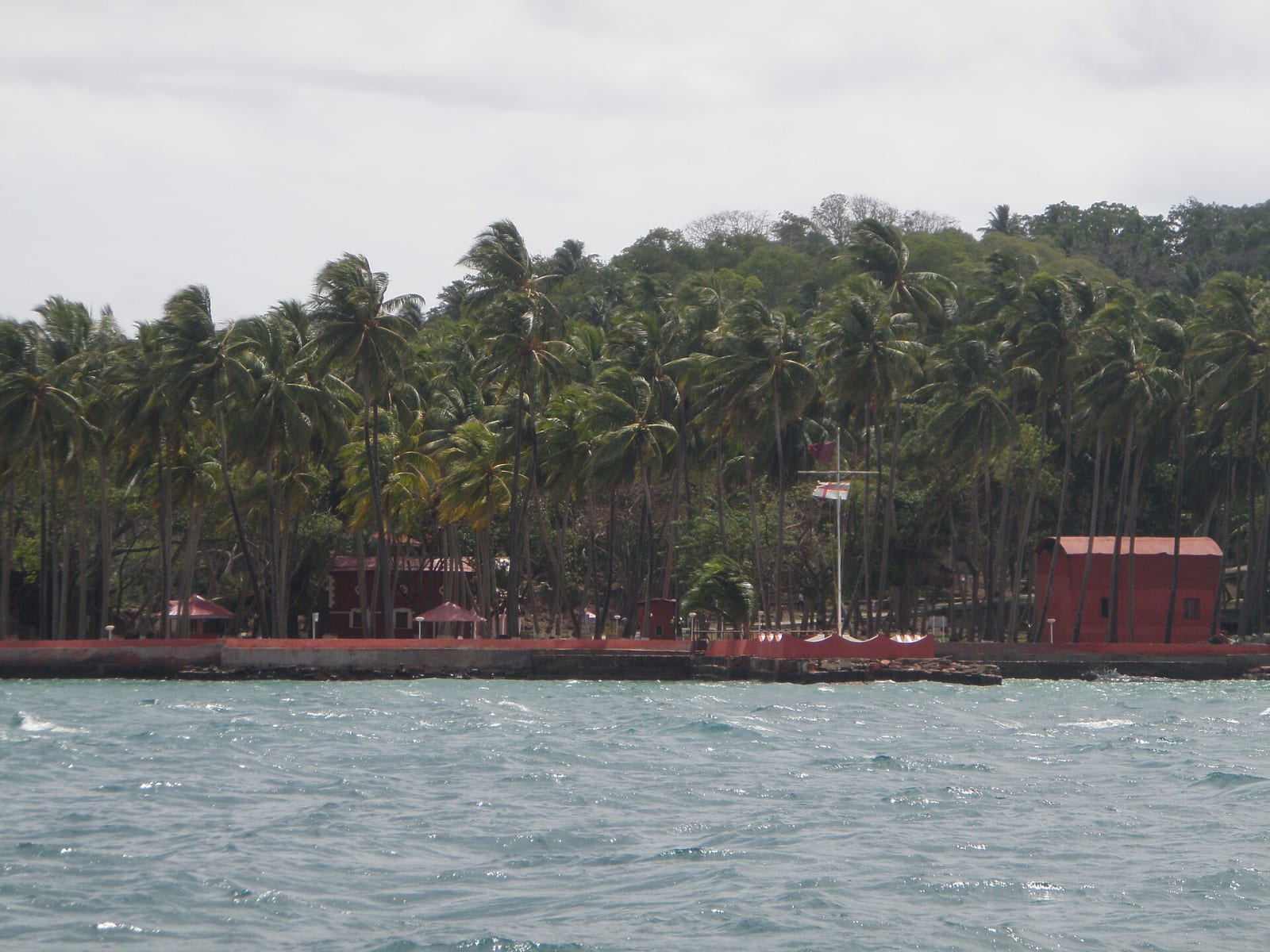 Ross Island seen from the water, with palms and a red-roofed building on the shore