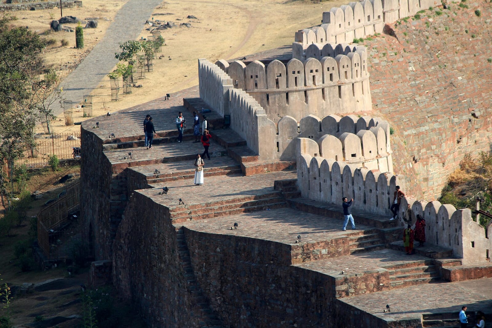 Steps and a broad rampart of the Kumbhalgarh wall with visitors walking on it