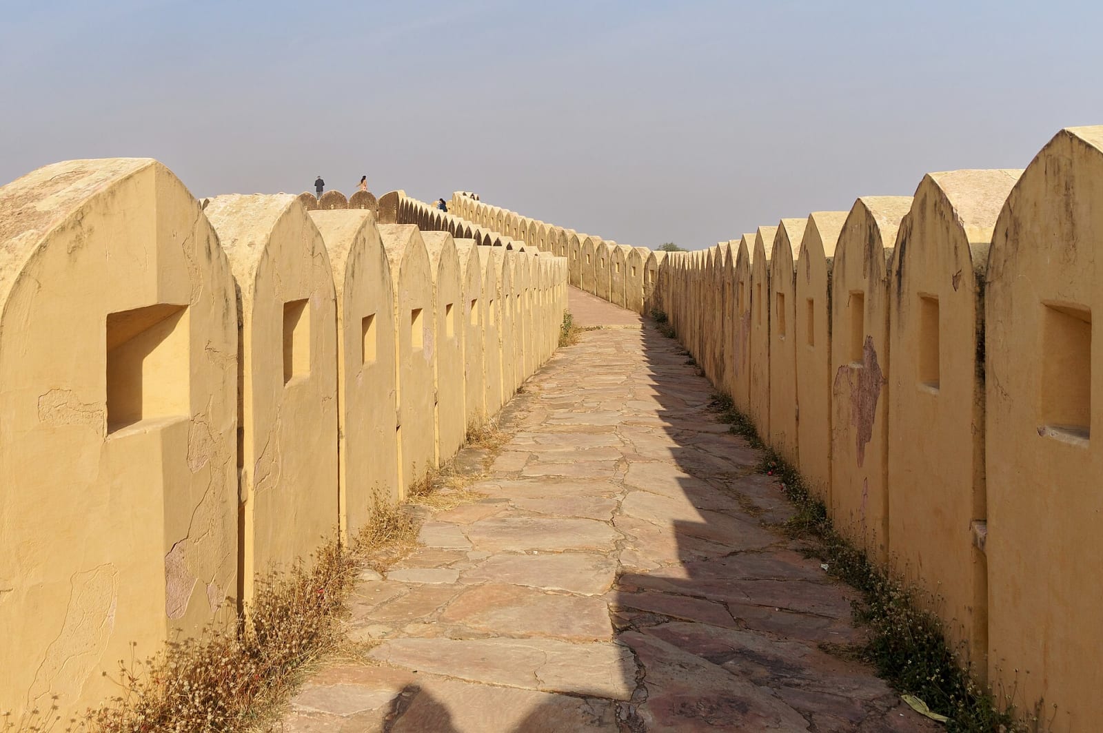 A stone walkway between scalloped parapet walls on the ramparts of Nahargarh Fort, Jaipur