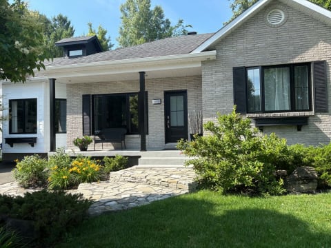 Façade avec fenêtres noires, volets et porte d'entrée noire à carrelage