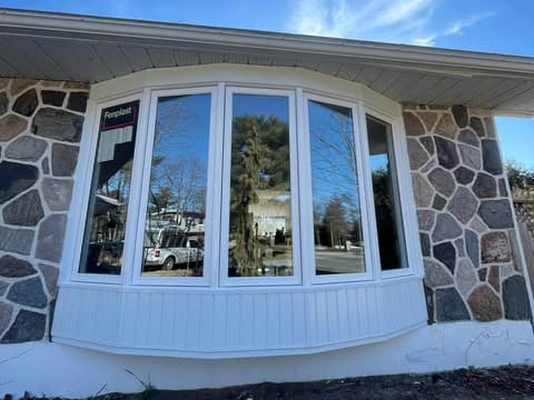 Fenêtre en baie arquée blanche en PVC sur une façade de pierre
