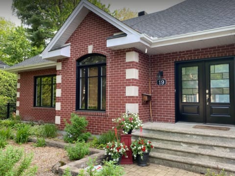 Façade classique en brique rouge avec fenêtres noires et porte double noire vitrée à carrelage