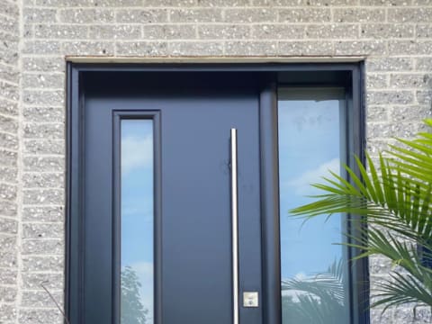 Porte d'acier contemporaine noire à poignée longue avec un latéral vitré