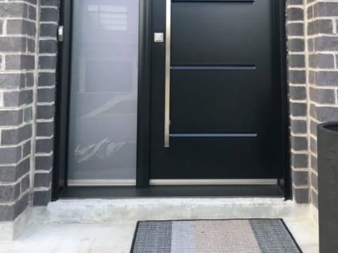Porte d'acier contemporaine noire à rainures et poignée longue avec un latéral givré