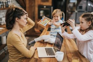 Working single mother feeling frustrated while her kids want to play with her at home