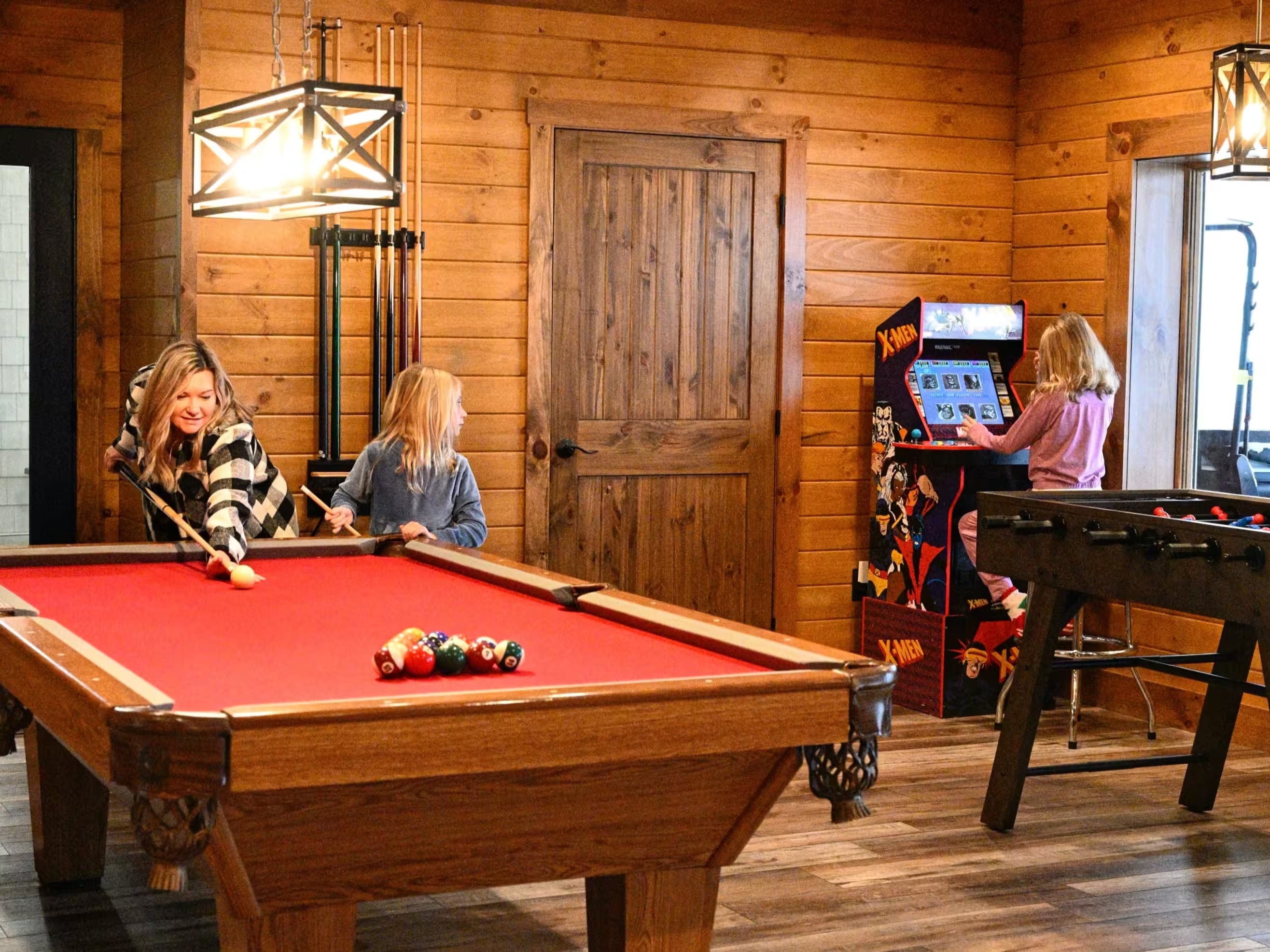 Family enjoying the indoor pool and arcade game room at Pool House Lodge