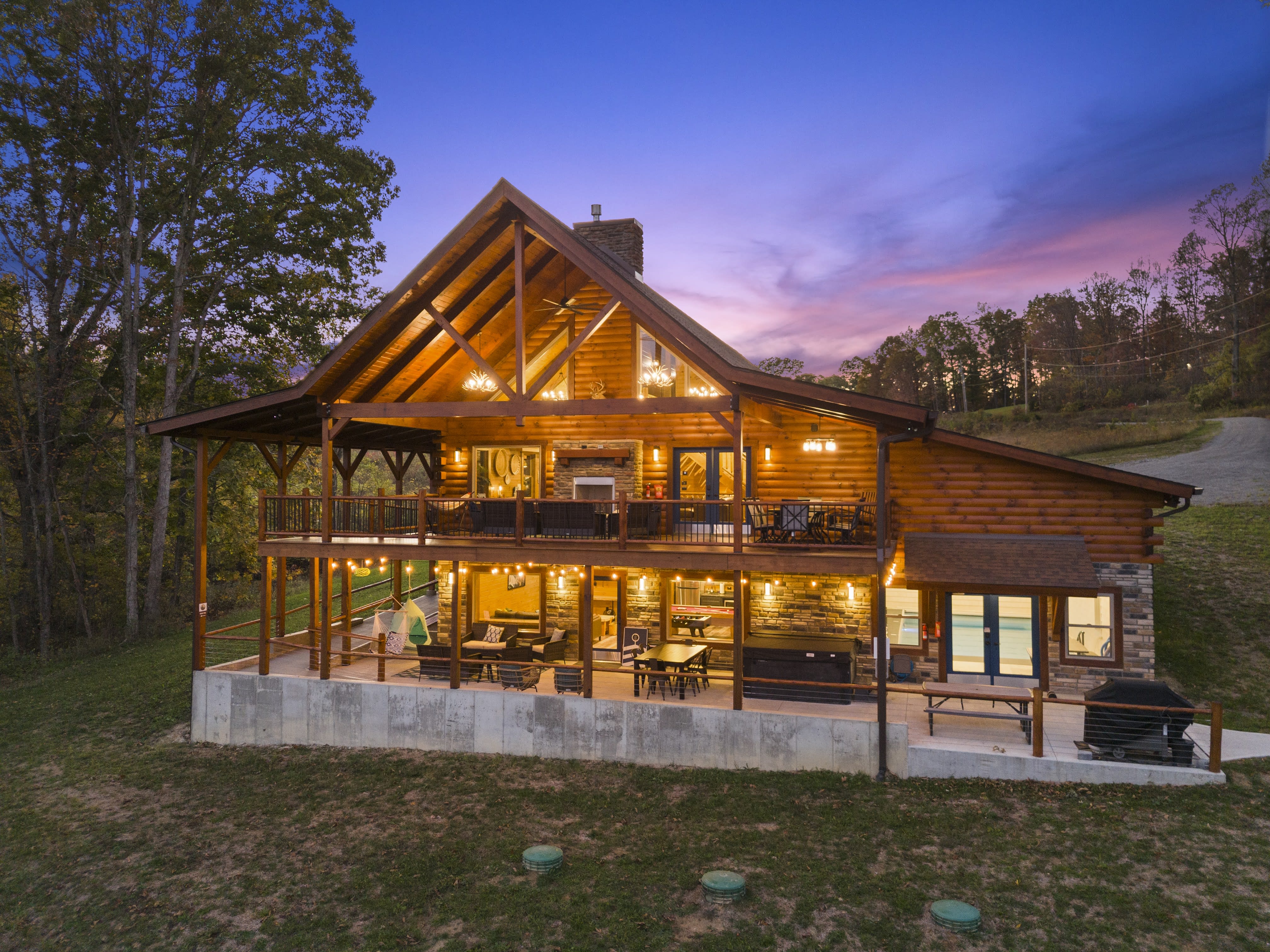 Pool House Lodge cabin exterior lit at dusk showing two levels and 22 wooded acres
