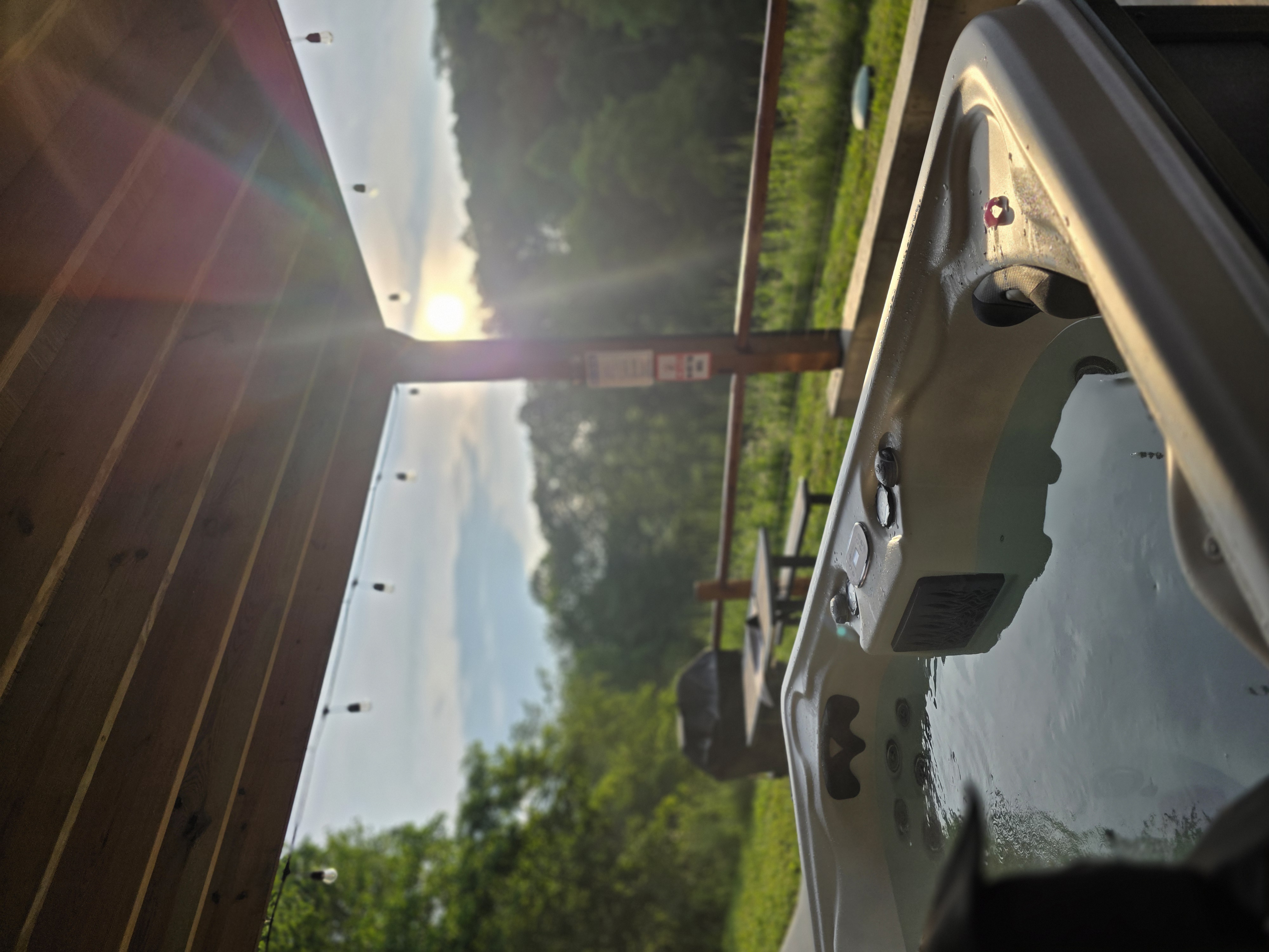 Hot tub at Pool House Lodge at sunrise in June, with string lights overhead and green hills visible in the background, Southern Region Hocking Hills Ohio