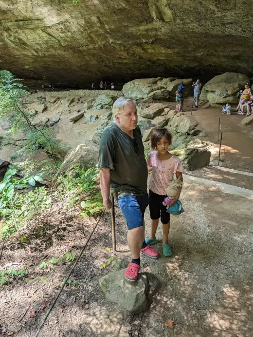 An adult and child standing on the trail beneath the Old Man’s Cave overhang.