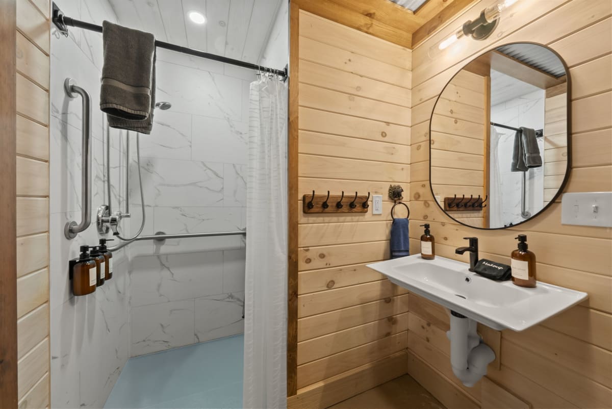 Accessible lower level bathroom at Pool House Lodge — marble transfer shower with grab bars, Hocking Hills Ohio cabin