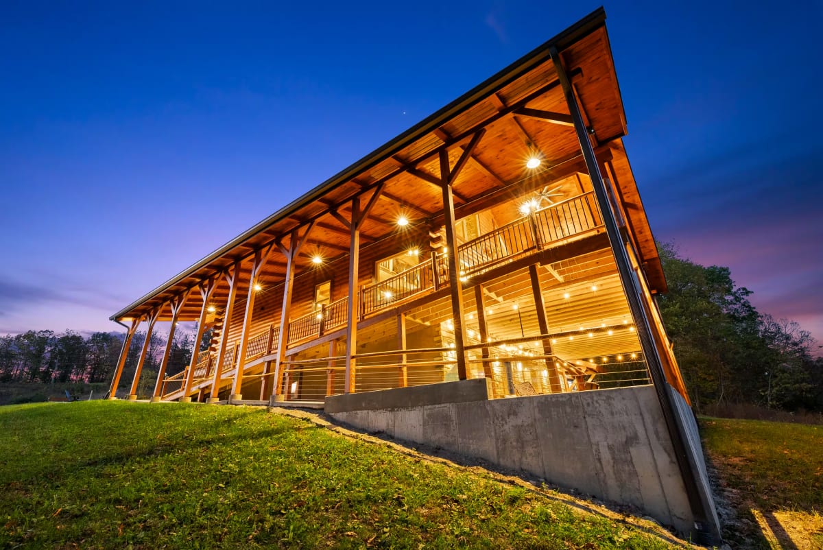 Covered exterior ramp and railings illuminated at dusk beside Pool House Lodge
