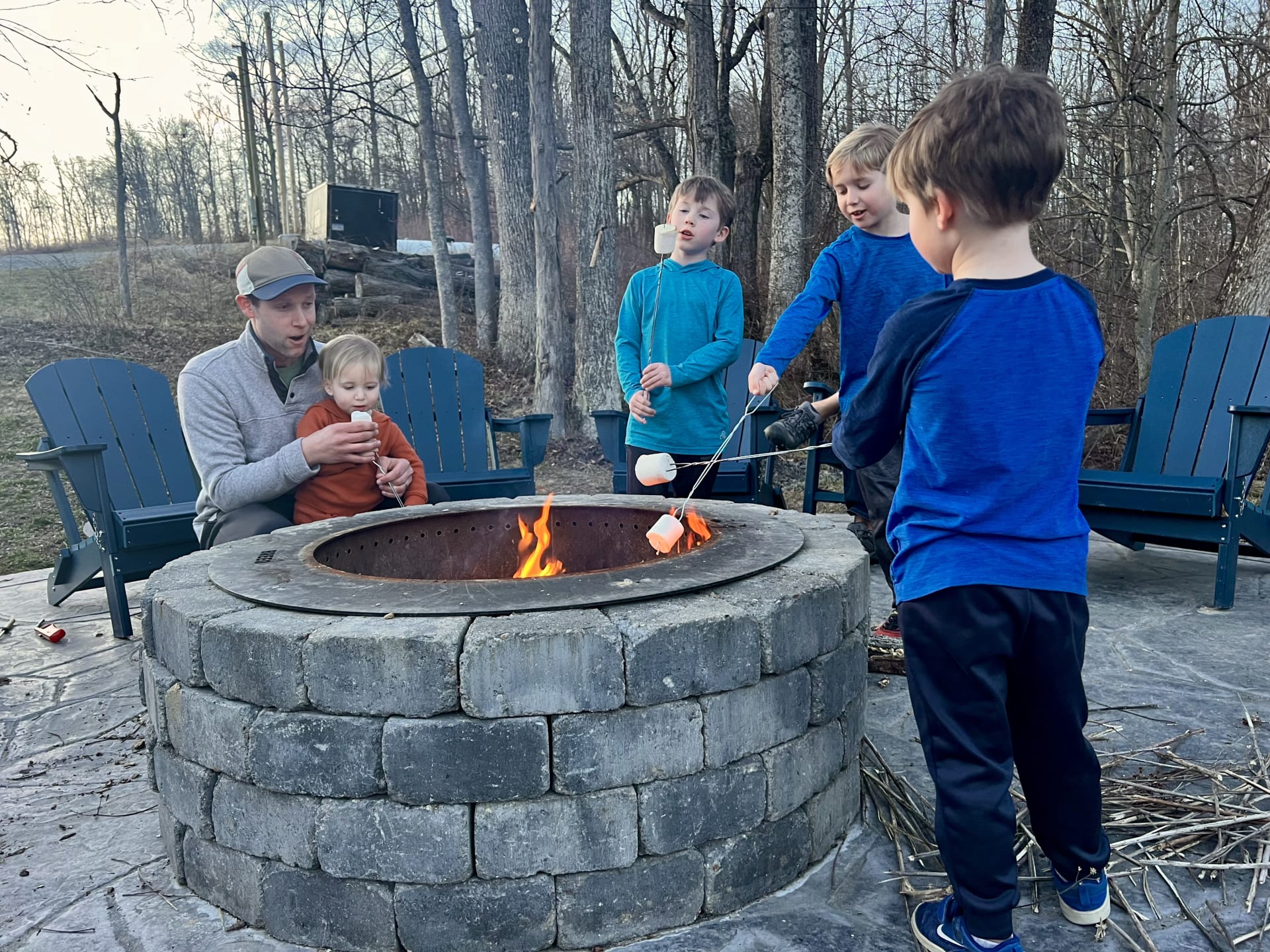 Dad and kids making s'mores at the fire pit at Pool House Lodge