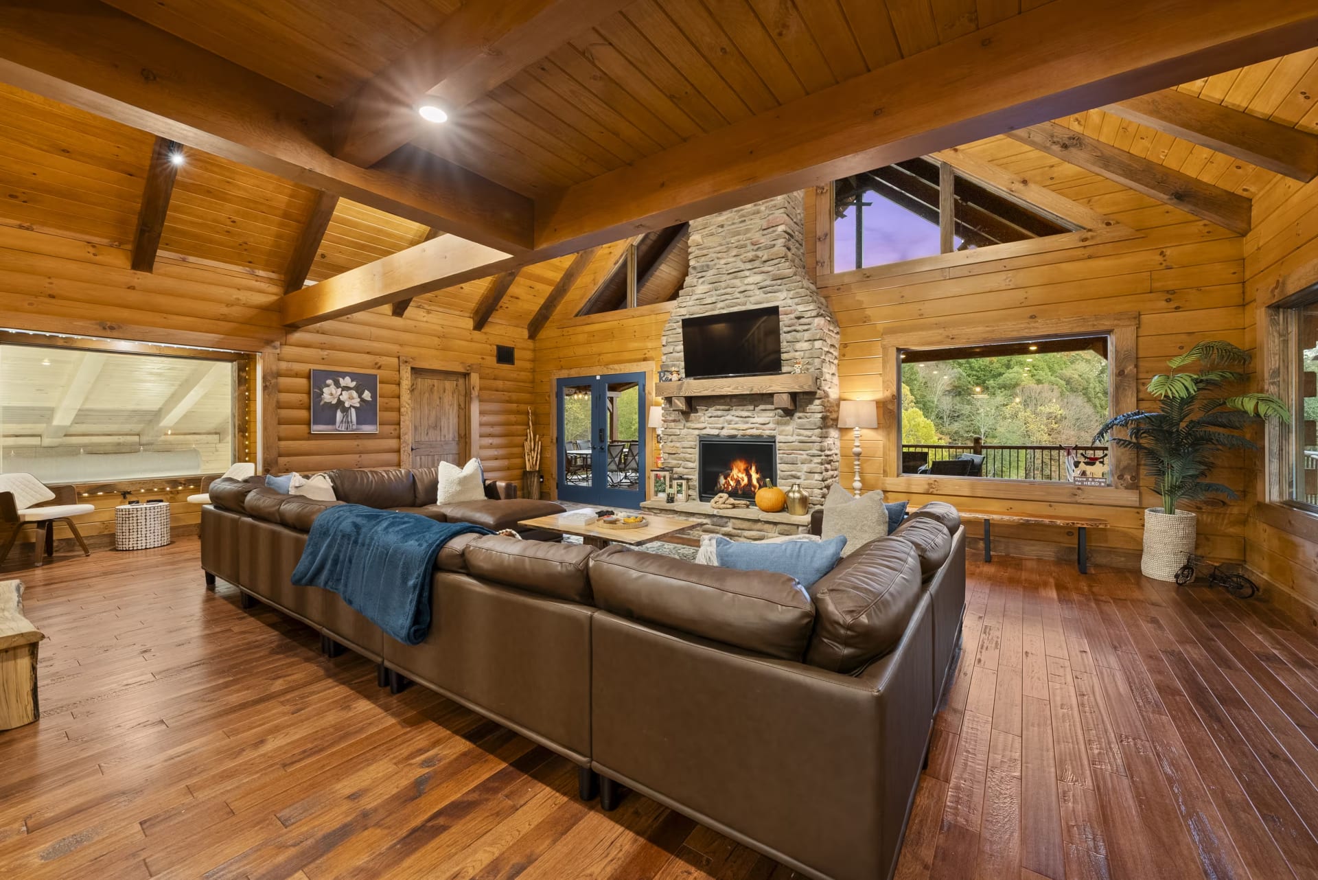 Living room with leather sectional and stone fireplace at Pool House Lodge