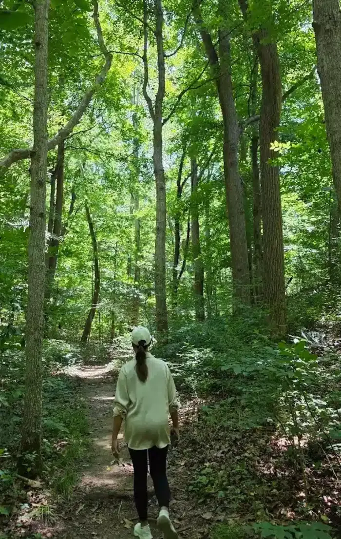 A visitor walking away along a narrow, unpaved woodland trail at Rockbridge State Nature Preserve.