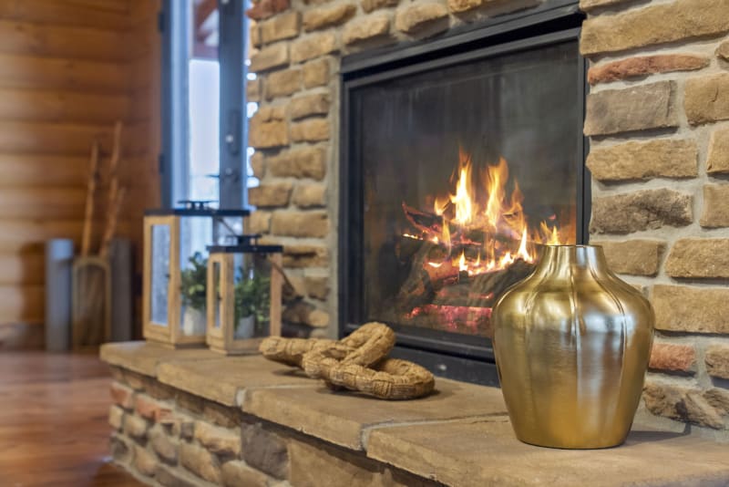 Pool house lodge stone fireplace burning fire gold vase mantle