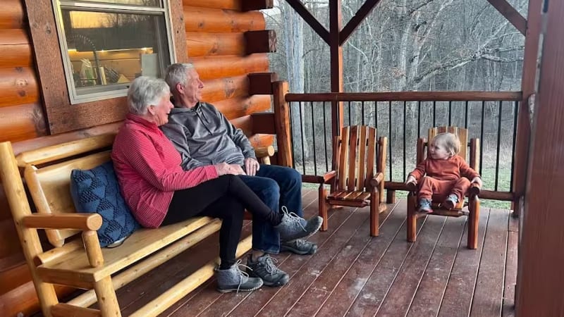 Grandparents and a toddler on the porch at Pool House Lodge