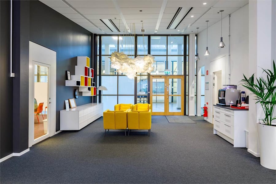 Linnégatan 89 B - Ljus yta med fåtöljer intill stora fönster från golv till tak.