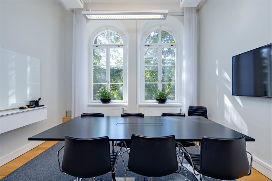 Valhallavägen 117 N - Mötesrum med utsikt mot grönskan via två bågformade fönster.