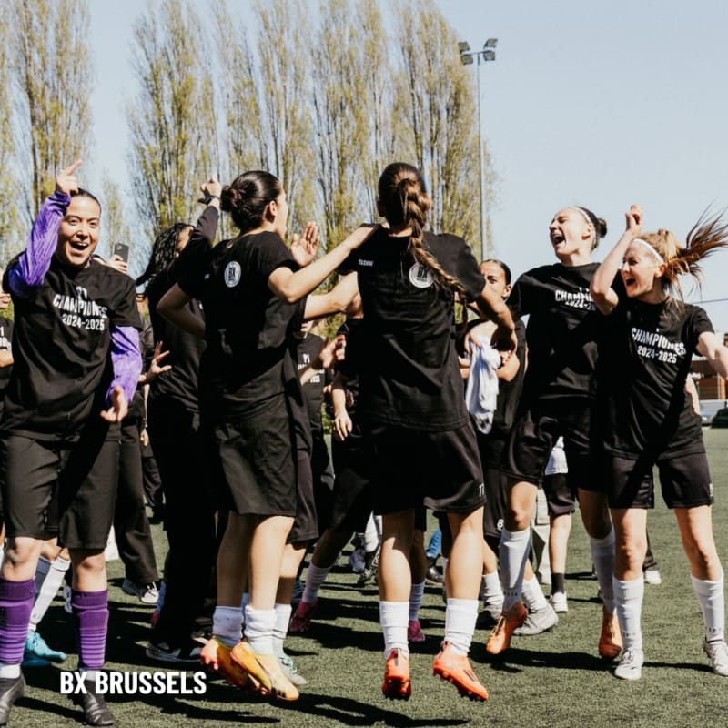 A group of female soccer players celebrate together on a field, wearing matching Champions 2022-2023 shirts.
