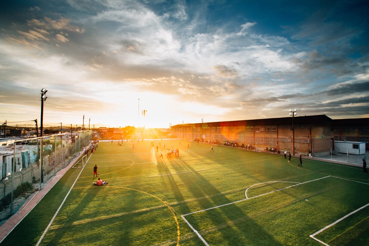 A vibrant soccer field bathed in sunset light with players scattered across.
