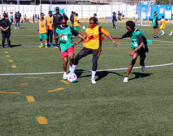 A group of girls engaged in soccer training, practicing skills and teamwork on a grassy field.