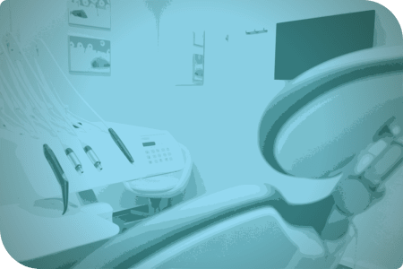 Una sala de tratamiento dental con una silla de examen y un monitor en la pared.