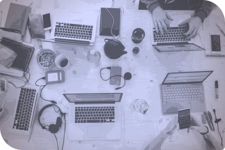 Un grupo de personas trabajando en sus computadoras en una mesa.