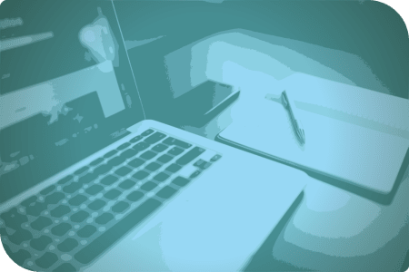 La computadora está en el escritorio, junto con un libro y un celular.