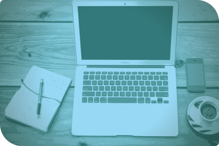 Laptop con una página en blanco y un bolso de notas en la mesa.