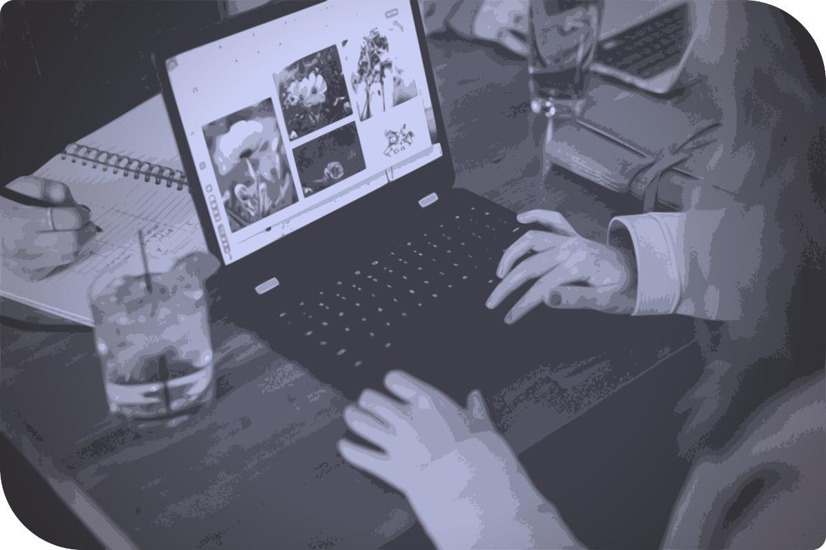 Una mujer usa un laptop en una mesa, mientras bebe un bebido.