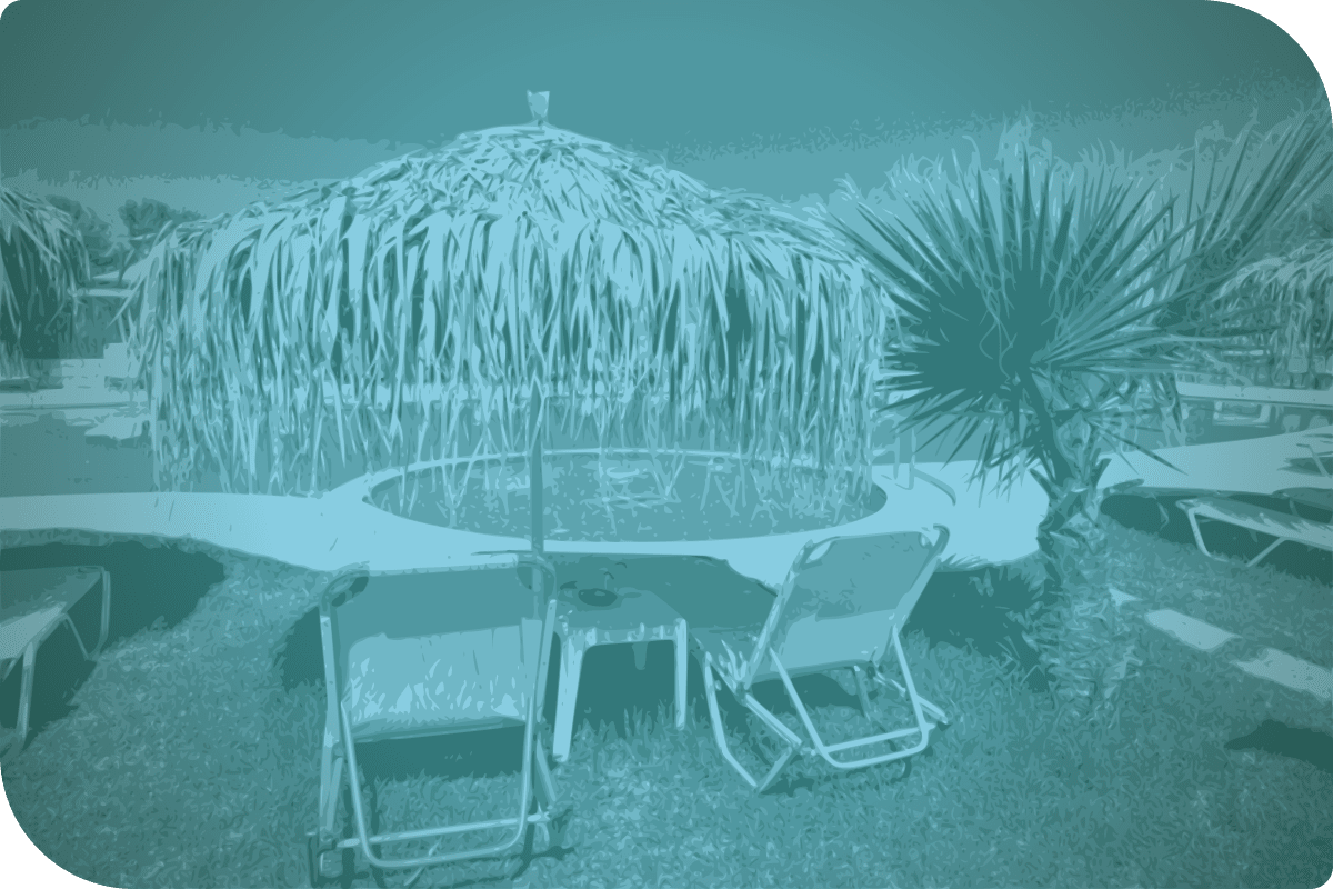 Una imagen de una palapa con una mesa y sillas al aire libre.