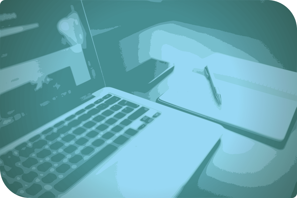 La computadora está en el escritorio, junto con un libro y un celular.