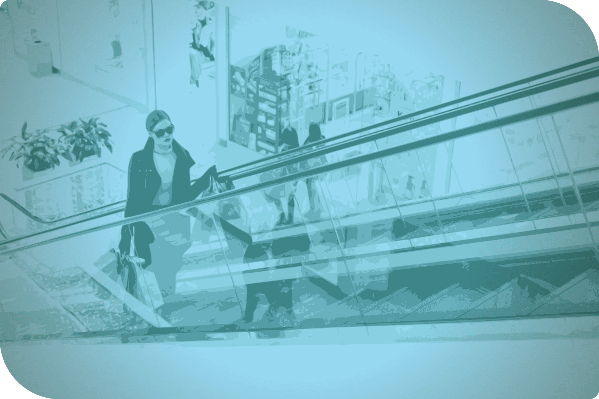 Una mujer con gafas de sol camina por un ascensor en un centro comercial.