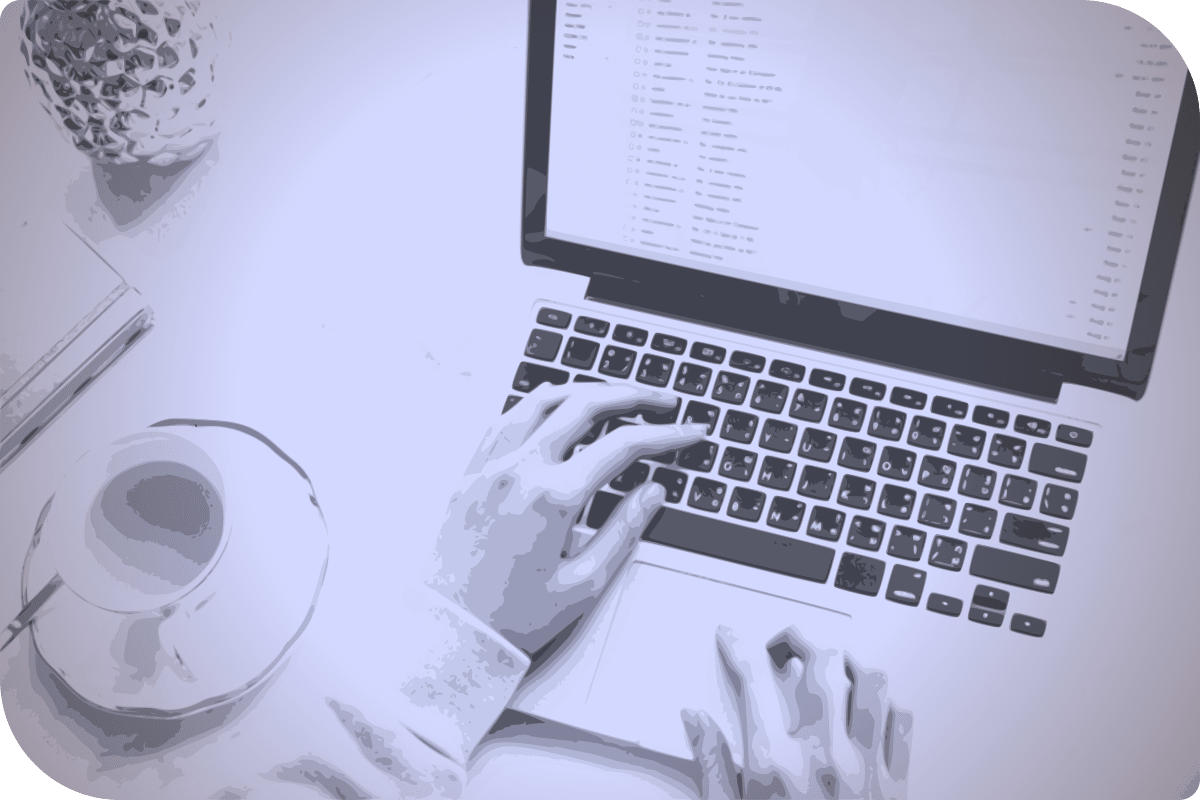 Una persona está trabajando en su computadora, con una taza de café a su lado.