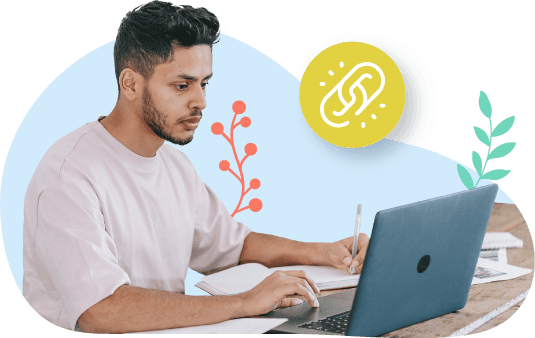 Un joven con barba escribe en un cuaderno mientras usa su computadora.