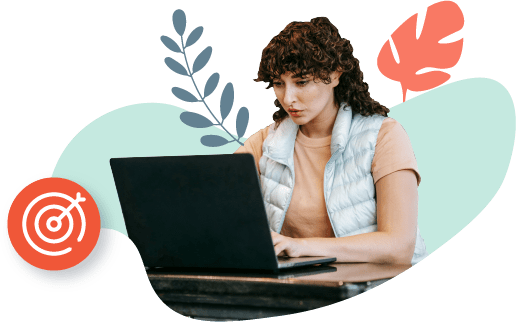 Una mujer joven está sentada en una mesa, usando su computadora portátil.