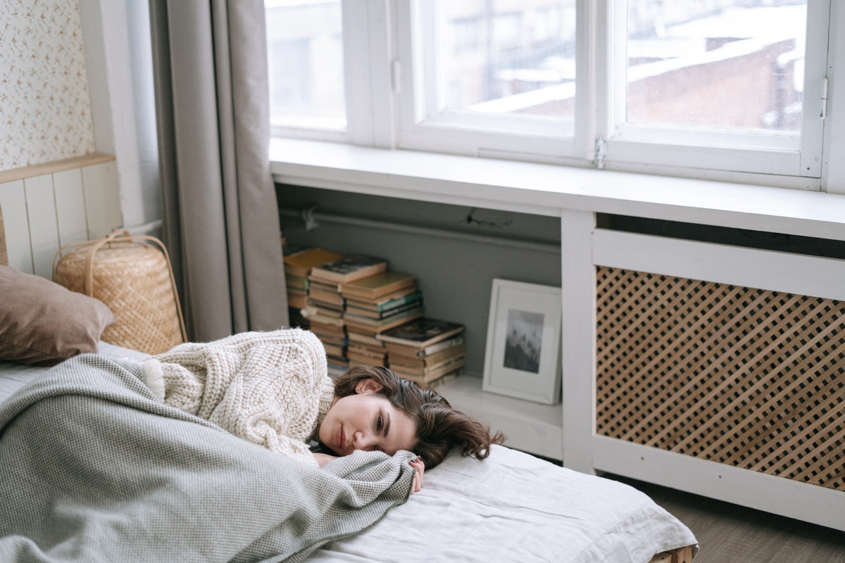 Mujer acostada en su cama sin energía.