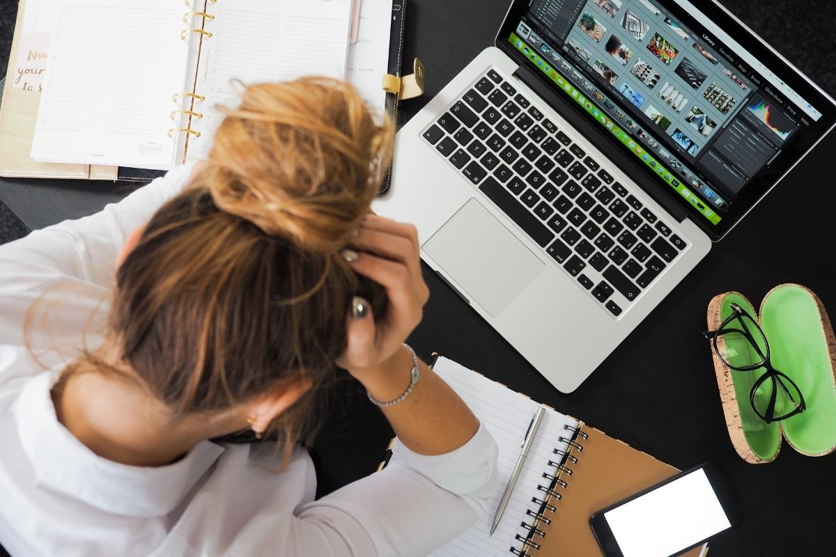 Mujer estresada en una mesa con un computador. 