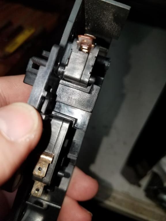 Lower door switch (top) with hole melted in plastic by terminal