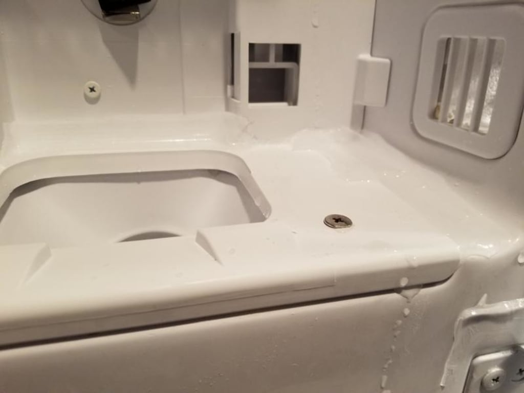 Water dripping from tray and freezing around ice bucket and inside.