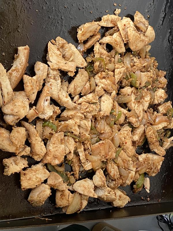 Seasoned and cooking pineapple chicken with onions and peppers