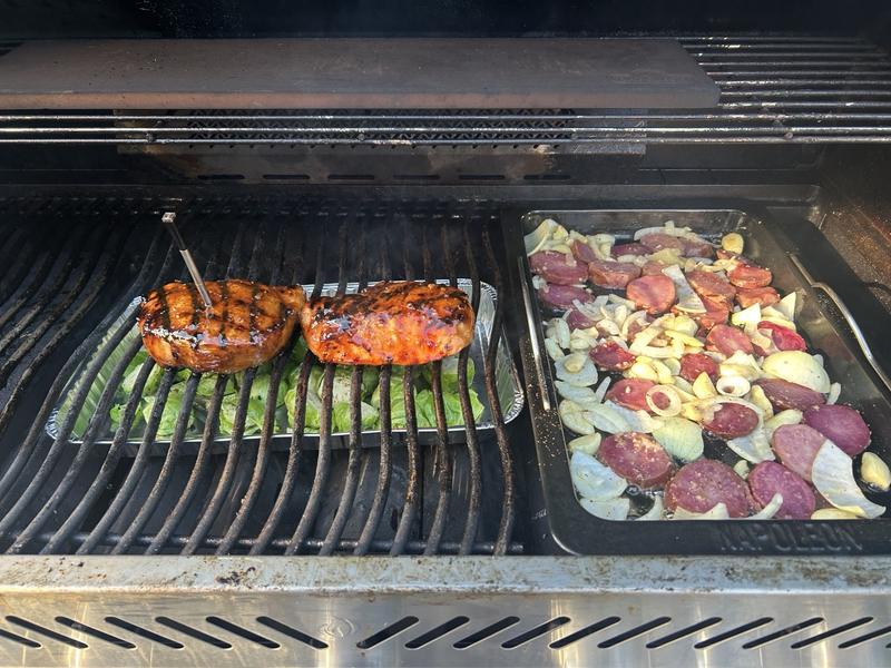 Teriyaki pork chops dripping onto brussel sprouts - potatoes, onions, garlic in roasting pan