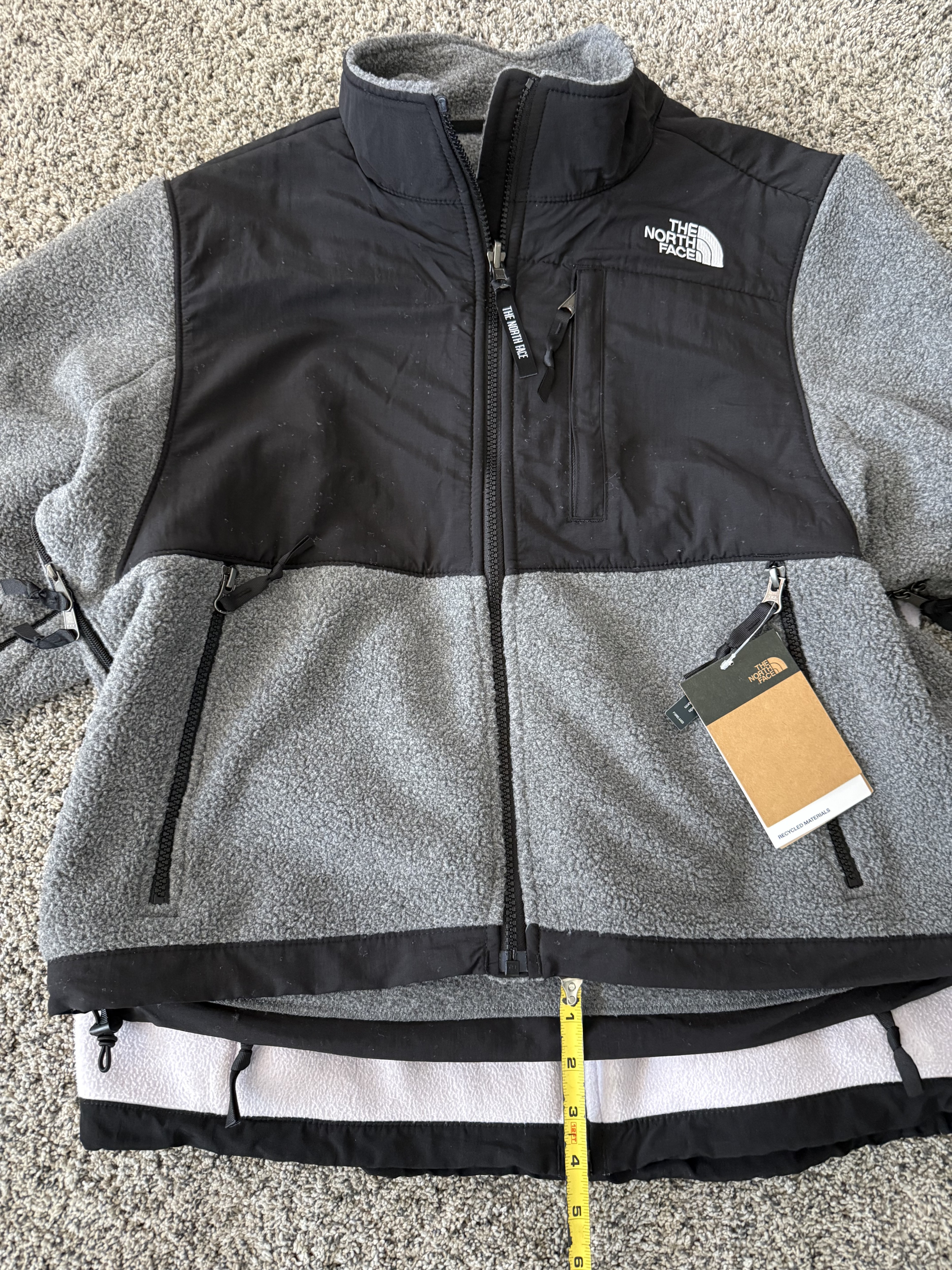 This is a photo of my new gray women's Denali jacket in size medium laying on top of my previous Lavender women's Denali jacket and medium. It is much shorter.