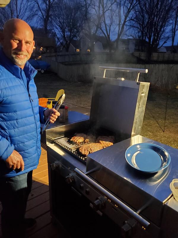 My husband grilling T bones on a cold, dark evening
