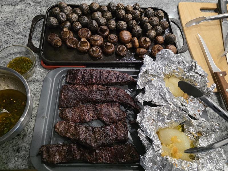 Grilling skirt steak, purple potatoes, mushrooms, garlic onions,  with chimichurri sauce on Cast Iron Charcoal and Smoker Tray
